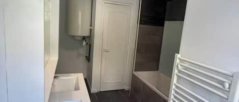Une petite salle de bain comprenant un lavabo, un miroir, des toilettes et un espace douche.
