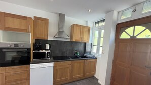 Een moderne keuken met houten kastjes, een vaatwasser, oven, magnetron en kookplaat.