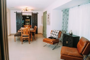 A dining area with a wooden table and chairs, a leather sofa, and a decorative cabinet. - Airport Family Getaway Pvt. Pickleball/Game Room (San Antonio)