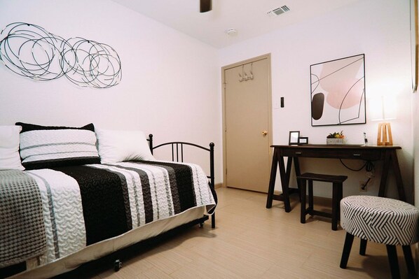 A bedroom with a bed, a desk, a chair, and a door. - Airport Family Getaway Pvt. Pickleball/Game Room (San Antonio)