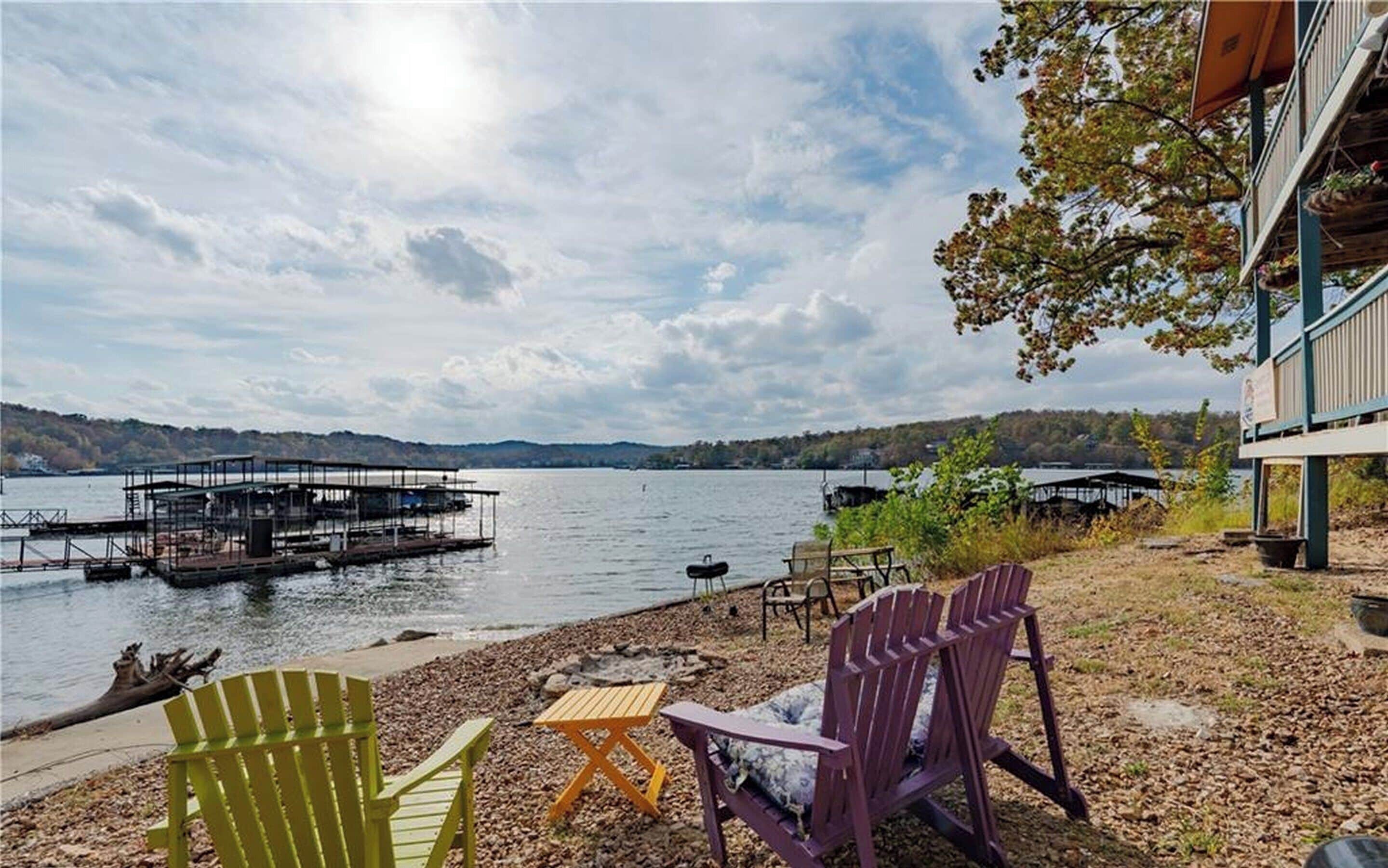 Une vue sur le lac, avec un quai, des chaises et un bâtiment doté d’un balcon surplombant l’eau.