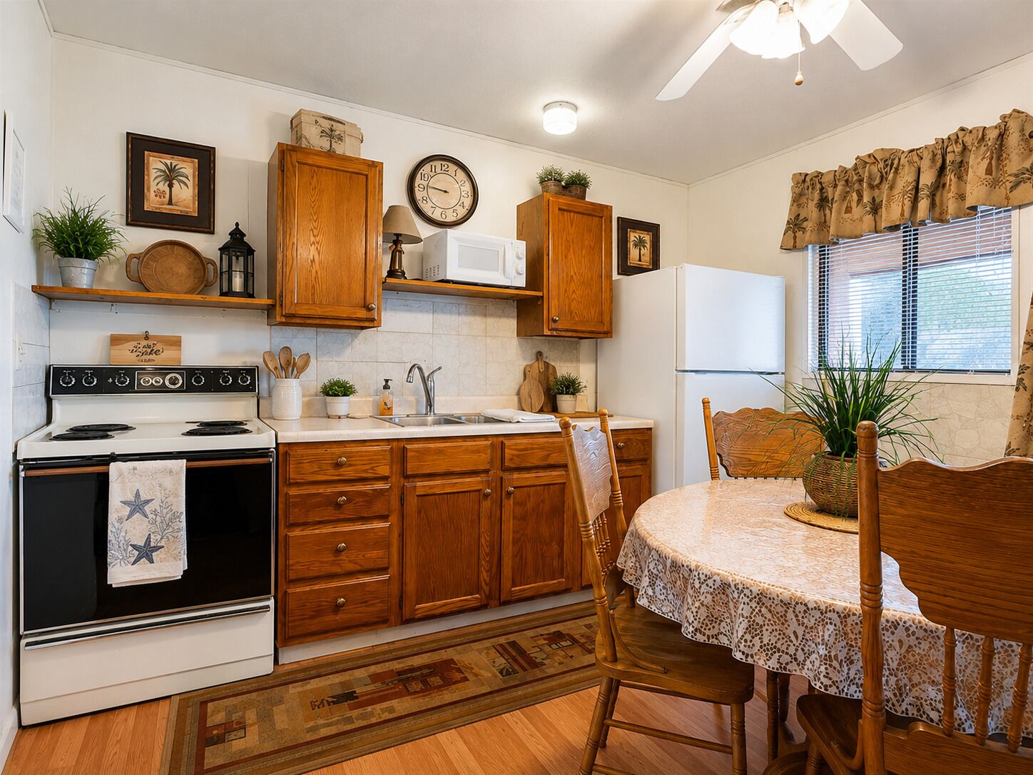 A kitchen with wooden cabinets, a stove, a microwave, and a dining area with a table and chairs.