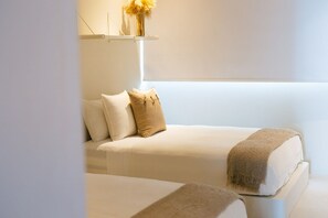 A minimalist bedroom with a bed, pillows, a bedside table, and a hanging light fixture.