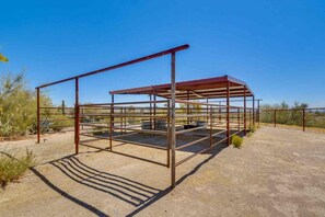Uma estrutura metálica com teto, possivelmente uma área coberta ou abrigo, em um ambiente desértico com vegetação escassa.