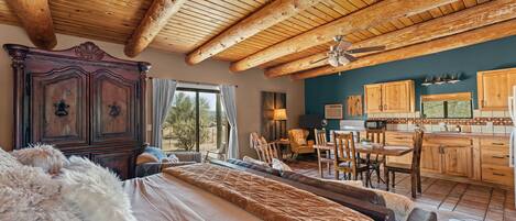 Un dormitorio amplio con una cama grande, techo de madera y vistas al exterior.