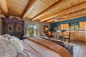 A spacious bedroom with a large bed, a wooden ceiling, and a view of the outdoors. - Casita with Horse Pens (Wickenburg)
