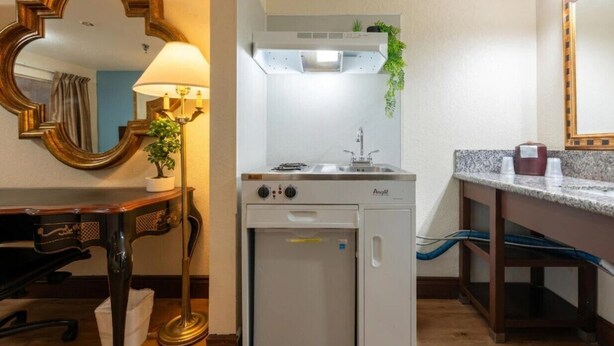 A compact kitchenette with a stove, sink, and a small refrigerator.