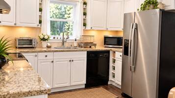 A modern kitchen with white cabinetry, a stainless steel refrigerator, a dishwasher, and a microwave.