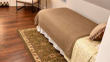 A bedroom with a bed, a chair, a small table with a candle, and a decorative vase.