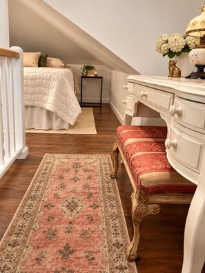 A bedroom with a bed, bedside table, dresser, bench, and a rug.