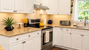 A kitchen with white cabinets, a stainless steel oven, a microwave, and a toaster.