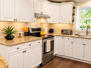 A kitchen with white cabinets, a stainless steel oven, a microwave, and a toaster.