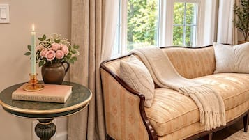 A cozy room with a sofa, a table with a book, a candle, and a vase with flowers.