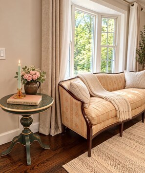 A cozy room with a sofa, a table with a book, a candle, and a vase with flowers.