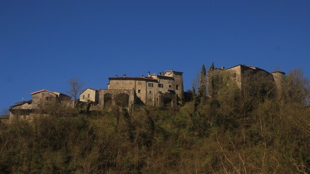 A historic stone building with multiple levels and a prominent tower, surrounded by dense shrubbery. - A sustainable and eco-friendly stone house near the Cinque Terre. (Villecchia)