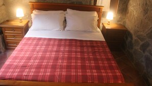 A bed with a wooden frame, white bedding, and a red plaid bedspread. There are two bedside tables with lamps on either side of the bed. - A sustainable and eco-friendly stone house near the Cinque Terre. (Villecchia)