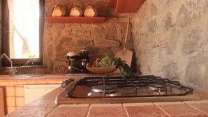 A kitchen with a gas stove, a coffee maker, and a basket of vegetables. - A sustainable and eco-friendly stone house near the Cinque Terre. (Villecchia)