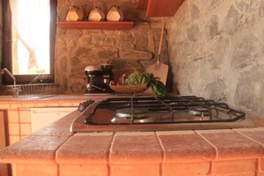 A kitchen with a gas stove, a coffee maker, and a basket of vegetables. - A sustainable and eco-friendly stone house near the Cinque Terre. (Villecchia)