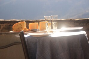 Uma mesa posta com pão, queijo e copos de água, com vista para o céu.