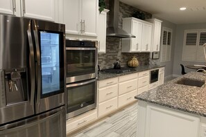 Una cucina moderna con elettrodomestici in acciaio inossidabile, mobili bianchi e un piano di lavoro in granito.