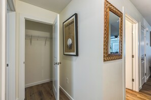 A hallway with a wooden floor, a framed picture on the wall, and a mirror with a decorative frame.
