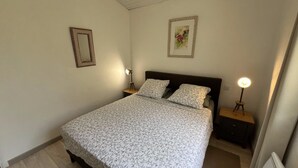 A bedroom with a bed, two bedside tables, a nightstand, a framed picture, and a lamp. - La Belle Aupsoise - AUPS (AUPS)