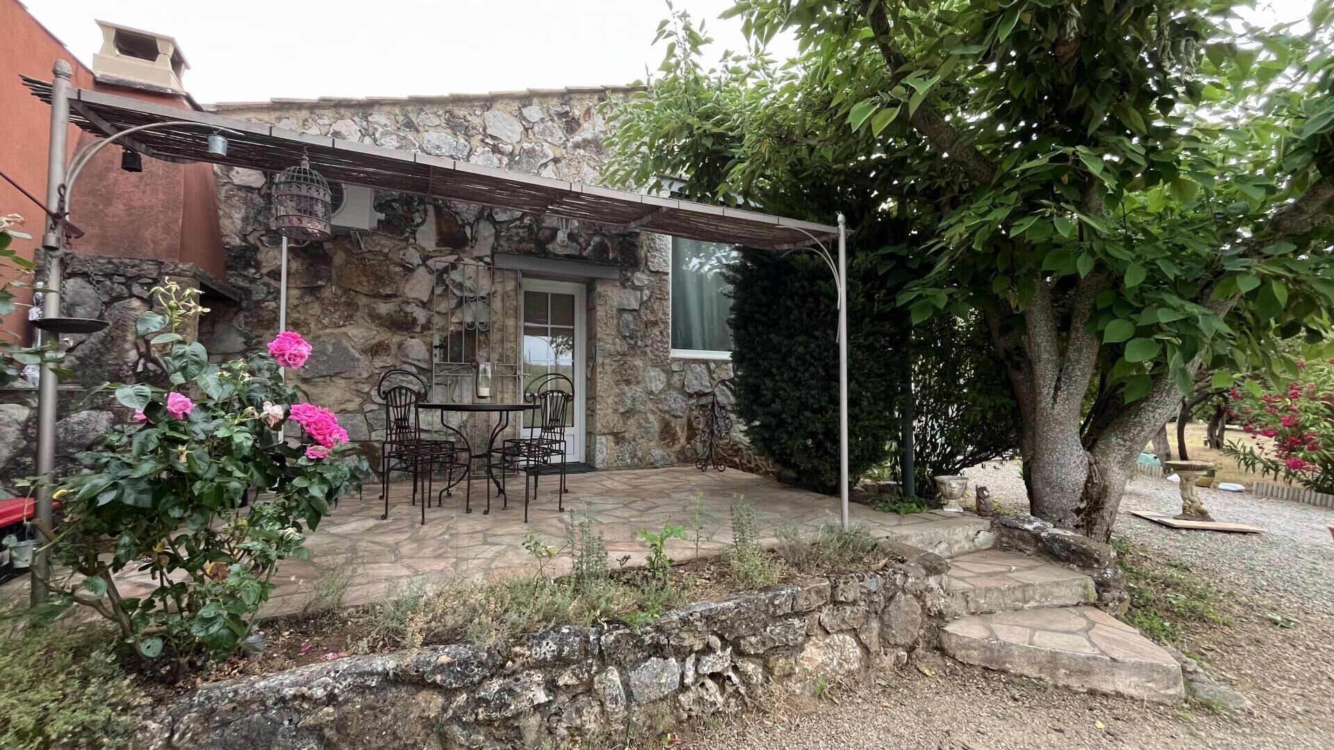 A stone building with a patio, outdoor seating, and a tree.