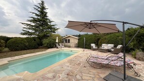 A backyard with a swimming pool, stone patio, lounge chairs, and a covered seating area. - La Belle Aupsoise - AUPS (AUPS)