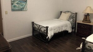 Ein Schlafzimmer mit einem Bett, einem Nachttisch, einer Lampe und einem Gemälde an der Wand.