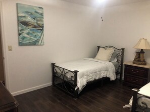 Ein Schlafzimmer mit einem Bett, einem Nachttisch, einer Lampe und einem Gemälde an der Wand.