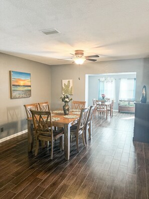 A dining area with a wooden table and chairs, a ceiling fan, and artwork on the walls. - 10 minutes from Rainbow Springs- My Peace River Ranch Stay in Dunnellon (Dunnellon)