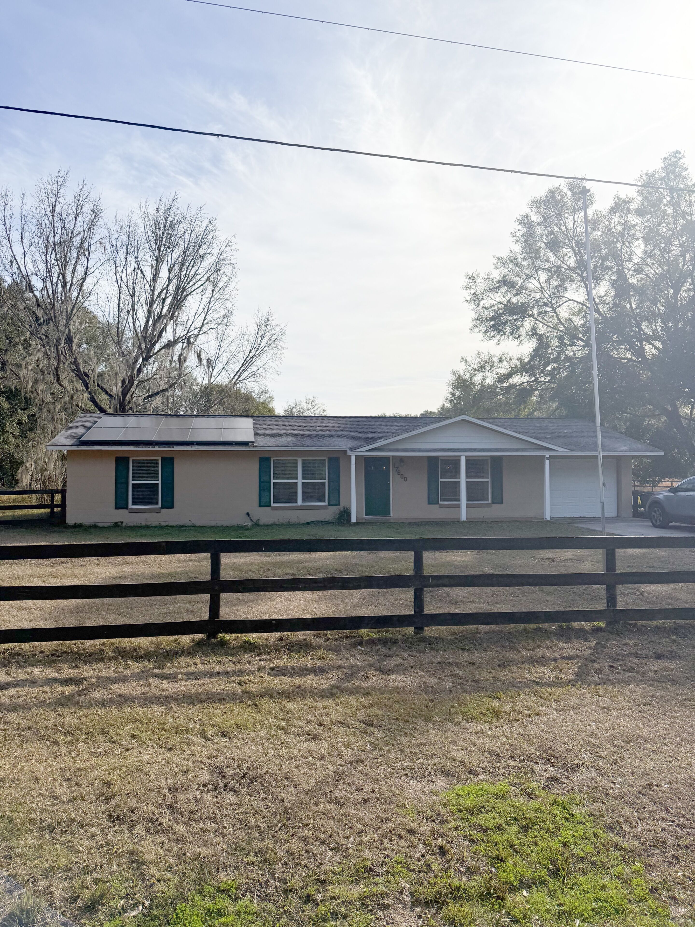 A single-story house with a sloped roof, a front porch, and a fenced yard.