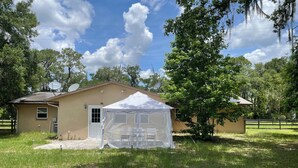 Ein Haus mit Satellitenschüssel, einem weißen Zelt und einem umzäunten Garten.