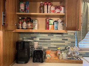 Eine Küche mit Holzausstattung, einer Kaffeemaschine, einem Toaster und verschiedenen Lebensmitteln auf der Arbeitsfläche.