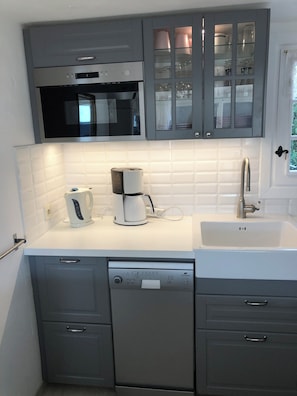 A modern kitchen with grey cabinetry, a built-in oven, a coffee maker, and a sink. - Villa Alizée (Bargemon)