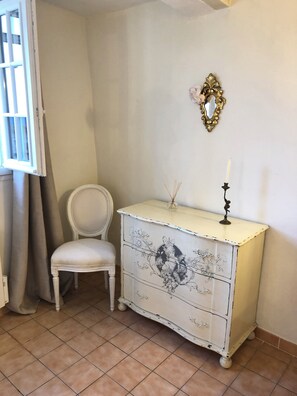 A room with a white chair, a white dresser with floral designs, a mirror, and a window with curtains. - Villa Alizée (Bargemon)