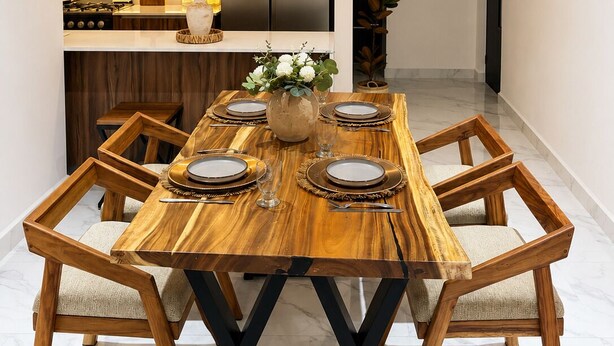 Un espace repas moderne avec une table en bois, six chaises et un vase central.
