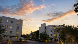 Un ensemble immobilier moderne comprenant plusieurs étages, un espace de stationnement et des espaces verts aménagés.