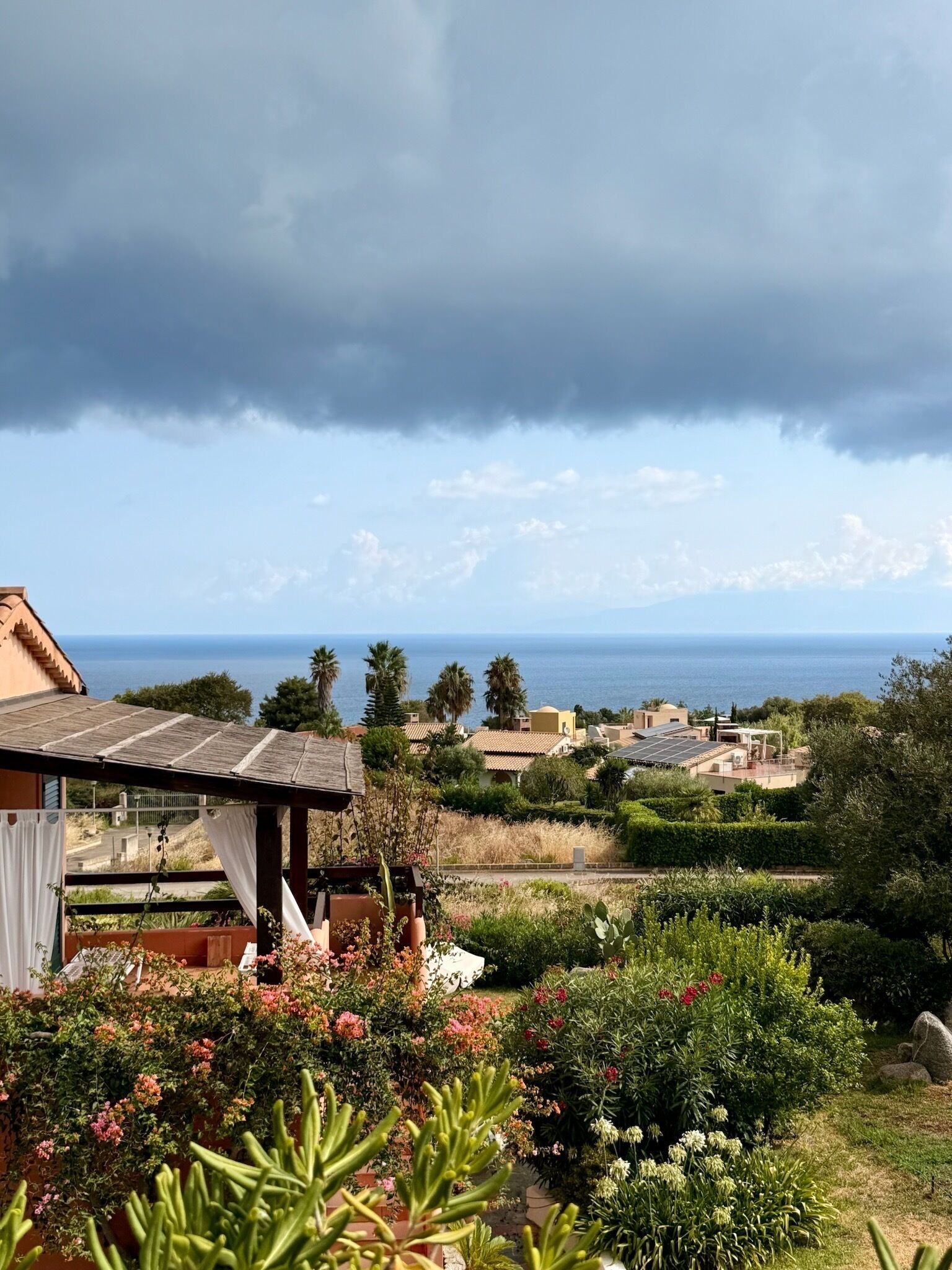 Une propriété située sur la côte, offrant une vue sur la mer, dotée d’un jardin avec différentes espèces de plantes et d’un bâtiment dont le toit est en pente.