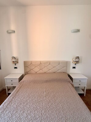 A bedroom with a tufted headboard, a patterned bedspread, and two bedside tables with decorative lamps. - Casa Sciaría: Relaxation with a Sea View in the Heart of the Costa degli Dei (Calabria)