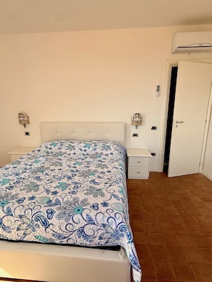 Ein Schlafzimmer mit einem Bett, Nachttischen, einem Kleiderschrank und einer Tür.