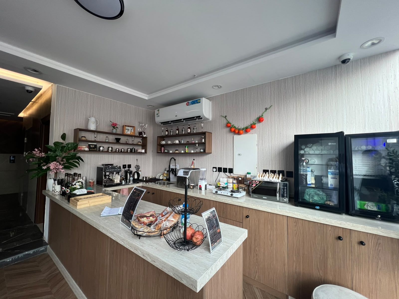 Una cocina moderna con encimera de mármol, cafetera y refrigerador.