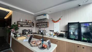 Una cocina moderna con encimera de mármol, cafetera y refrigerador.