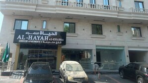 A multi-story building with a sign for 'AL-HAYAH KHADRA Serviced Apartments'.