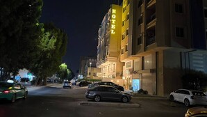 A hotel with a prominent yellow sign, multiple floors, and parked cars on the street.