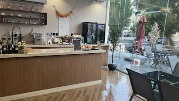 A modern reception area with a wooden counter, various kitchen appliances, and a view of the outdoors.