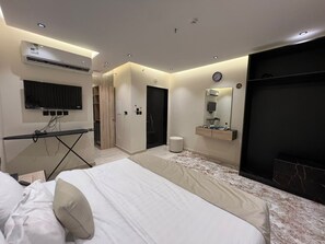 Un dormitorio moderno con cama, televisor, espejo y armario empotrado.