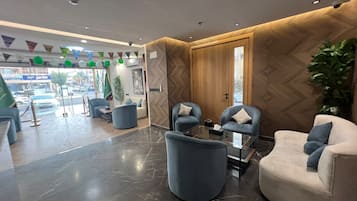 A modern lobby with a reception desk, seating area, and a view of the street outside.