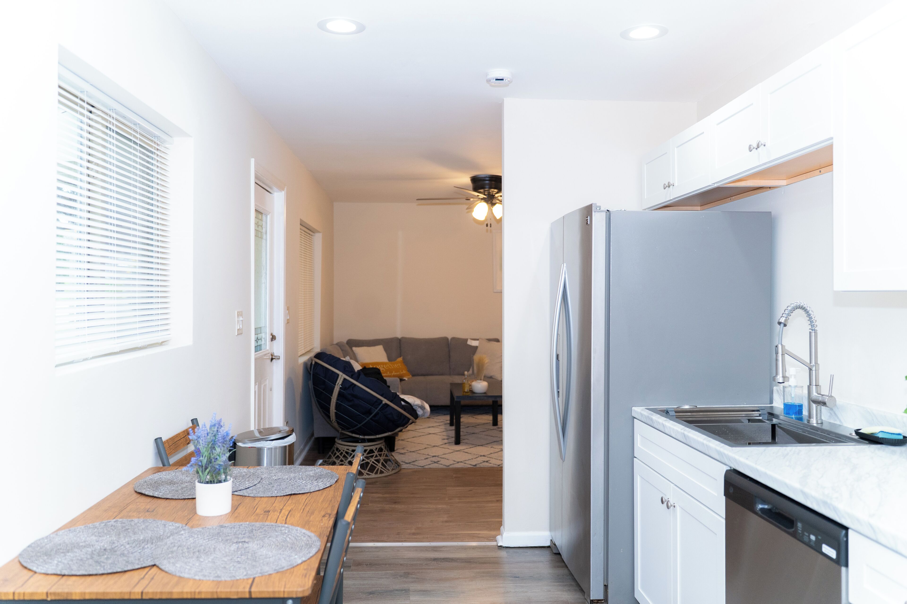 A modern kitchen with a built-in dishwasher, a grey refrigerator, and a white countertop.