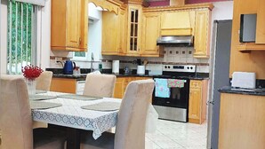 A kitchen with wooden cabinets, a dining table with chairs, and a tiled floor.
